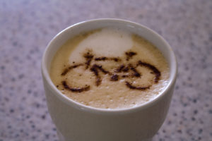 Cup of coffee with a bicycle image dusted on top